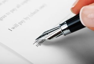 Hand signing official document with fountain pen – representing NRIWAY’s trusted verification and attestation services for NRIs.